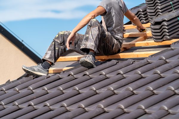 installation of roofing by a craftsman, ceramic tiles on wooden beams.