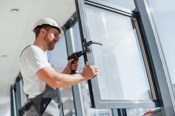 Installing new windows. Close up view of repairman that is working indoors in the modern room.